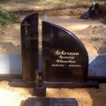 Pulēts melnā granīta piemineklis ar pusslēgtu kapu rāmīti